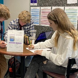 Students tutoring other students at a library table.